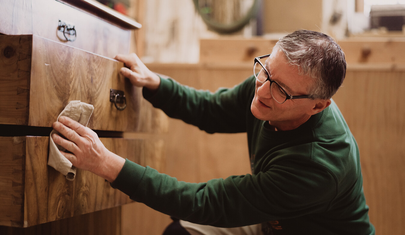 Schreinermeister Marc Bell-Schäfgen behandelt Massivholz-Kommode bei einem Innenausbau-Projekt