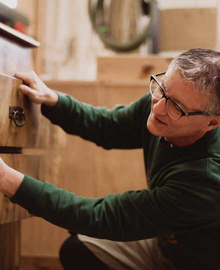 Schreinermeister Marc Bell-Schäfgen behandelt Massivholz-Kommode bei einem Innenausbau-Projekt